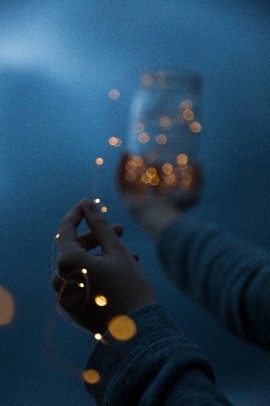 A hand drawing fairy lights from a clear mason jar in the dark