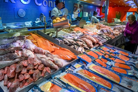 A woman looks over some seafood choices in a market.